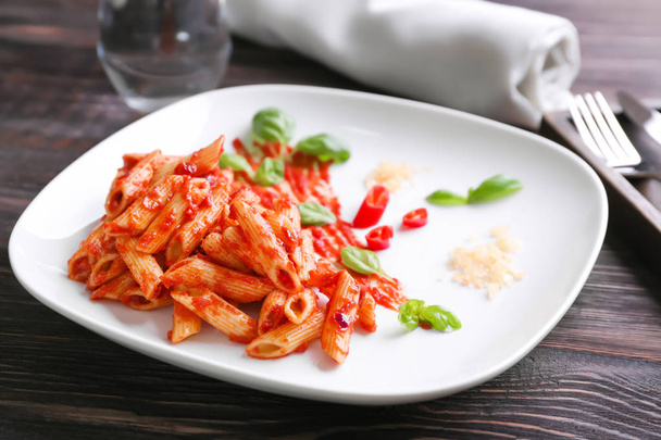 Plate with delicious penne pasta and sauce on table - Foto, Imagem