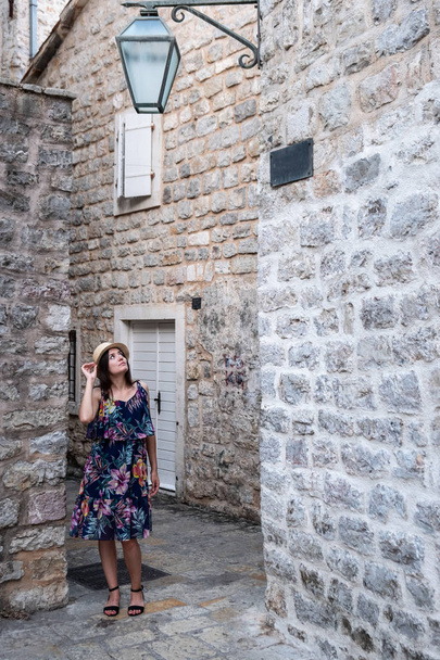 Europe summer travel mediterranean destination. Tourist woman on vacation, walking on the streets of old and beautiful Mediterranean city in hat and summer dress - Photo, image