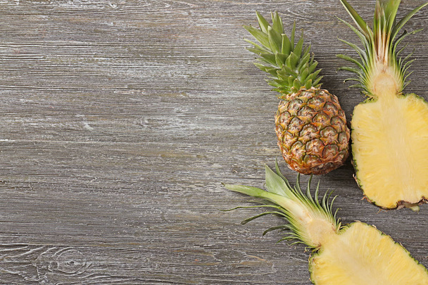 Whole and cut ripe pineapples on wooden background - Photo, Image