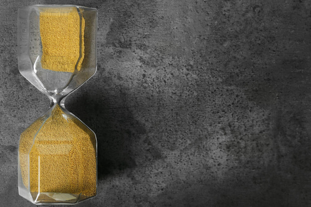 Hourglass on grey textured background. Time management concept - Photo, Image