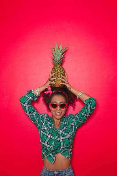 Hermosa mujer afroamericana con piña sobre fondo de color - Foto, imagen
