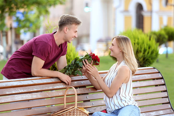 Jeune homme donnant des fleurs à sa petite amie sur la date romantique en plein air
 - Photo, image