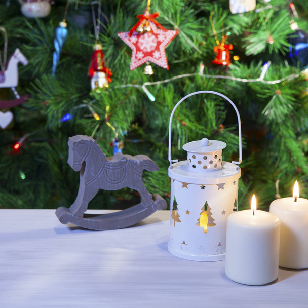 the Christmas mood. Candles and lantern under the Christmas tree as a new year card - Photo, Image