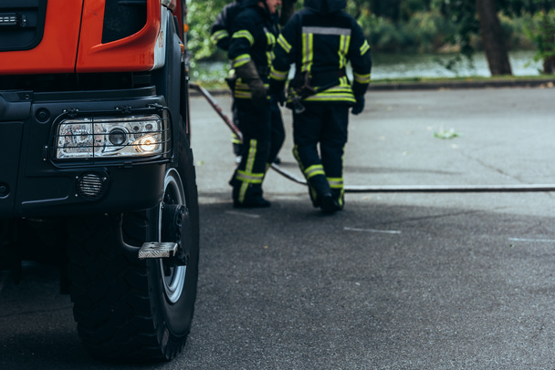 частковий вид на бригаду пожежників і водяний шланг на землі на вулиці
 - Фото, зображення