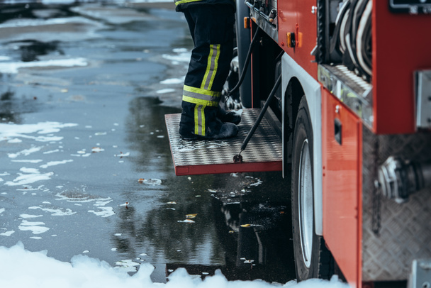 обрізаний постріл пожежника у вогнетривкій формі, що стоїть на пожежній машині на вулиці
 - Фото, зображення