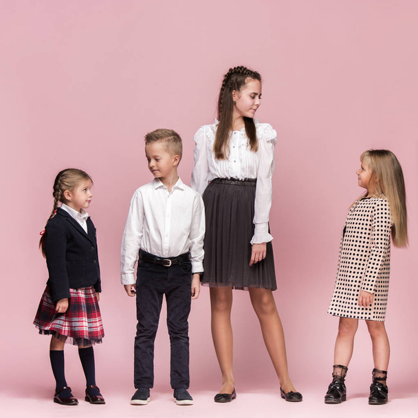 Cute stylish children on pink studio background. The beautiful teen girls and boy standing together - Fotó, kép