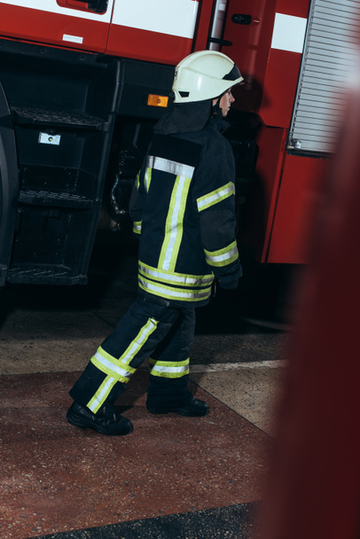 female firefighter in uniform and helmet walking at fire station - Fotoğraf, Görsel