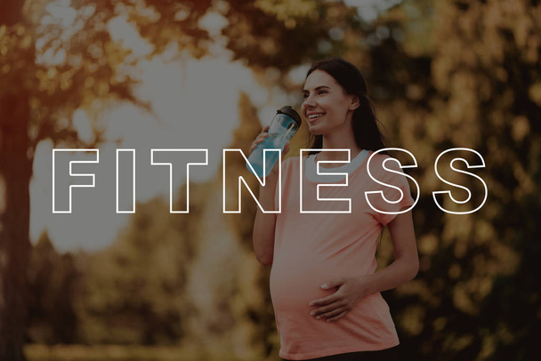 Smiling. Pregnant. Woman. Pink T-shirt. Walk. Park. Sports Bottle. Beautiful. Belly. Bodycare. Crossfit. Exercise. Happiness. Healthy Lifestyle. Mom. Nature. Sportswear. Fitness Mat. - Foto, immagini