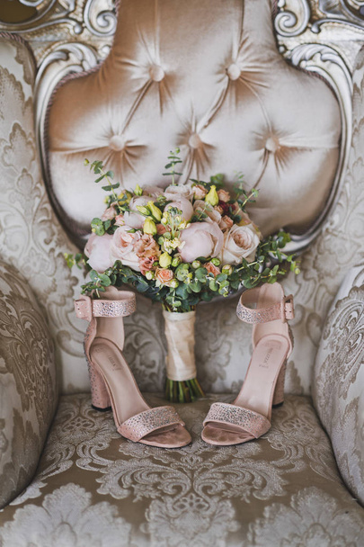 Bouquet da sposa di rose e scarpe rosa sulla sedia imperiale
. - Foto, immagini