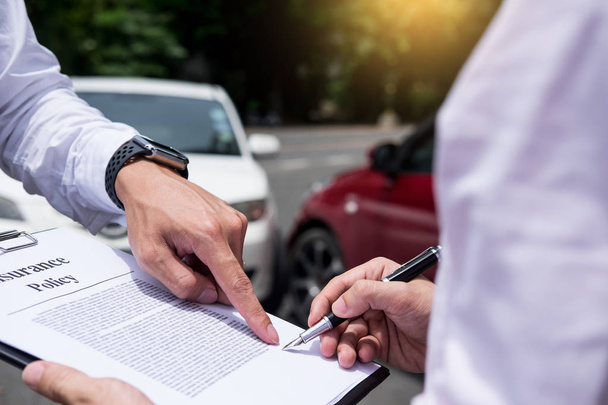 Страховий агент пише в кишені під час вивчення автомобіля після того, як вимога про нещасний випадок оцінюється і обробляється
 - Фото, зображення