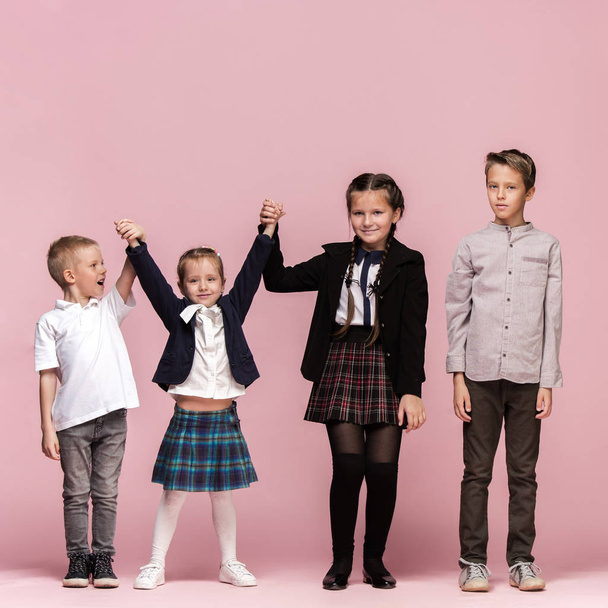 Cute stylish children on pink studio background. The beautiful teen girls and boy standing together - Fotoğraf, Görsel
