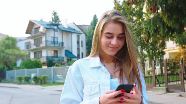 Kobieta za pomocą Smartphone wyglądający zadowolony - Materiał filmowy, wideo