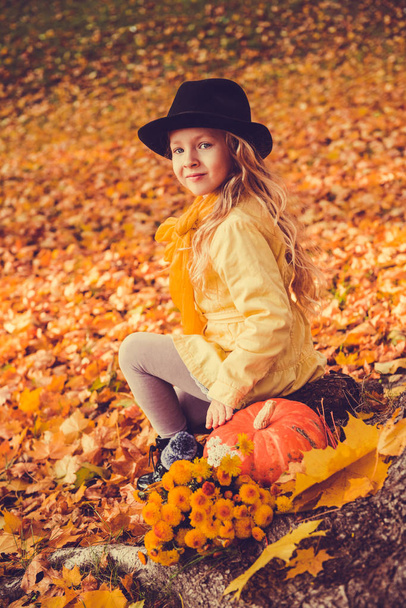 Petite belle fille blonde avec une grosse citrouille en fond d'automne
 - Photo, image