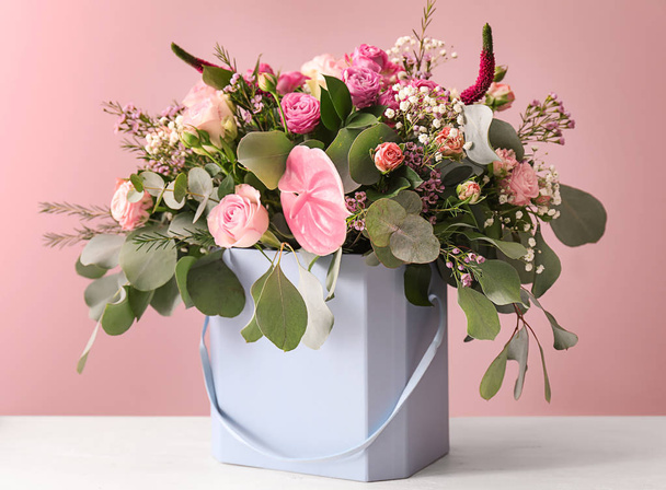 Подарочная коробка с красивыми цветами на столе на фоне цвета - Фото, изображение