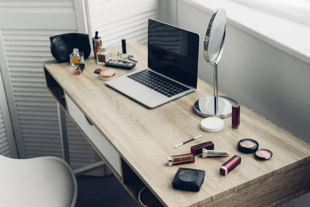 Close-up shot van werkplek met laptop en make-up benodigdheden thuis - Foto, afbeelding
