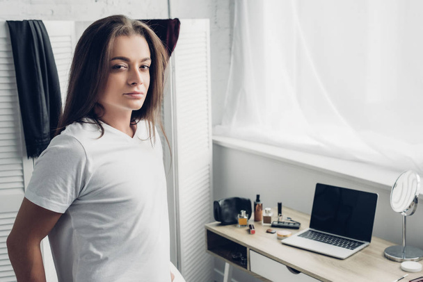 close-up portrait of young transgender woman standing near workplace and looking at camera at home - Fotoğraf, Görsel