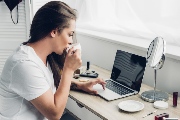 young transgender freelancer woman drinking coffee while working with laptop  at home - Photo, Image