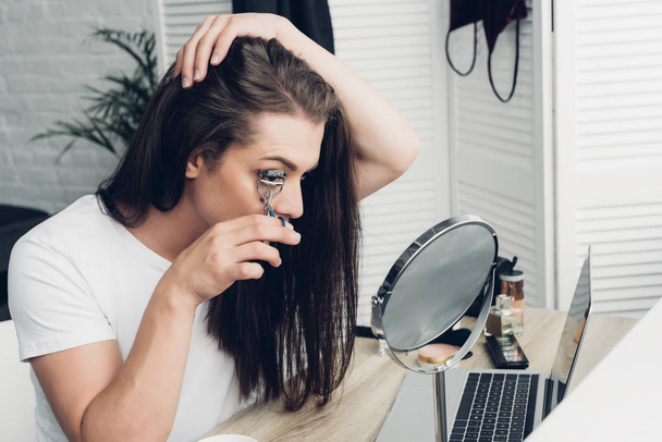 young transgender woman doing makeup with lash curler at home - Zdjęcie, obraz
