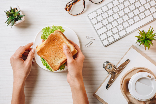Oříznout obrázek podnikatelka oběd sendvič a kávy v pohárek u stolu s klávesnice počítače v kanceláři  - Fotografie, Obrázek