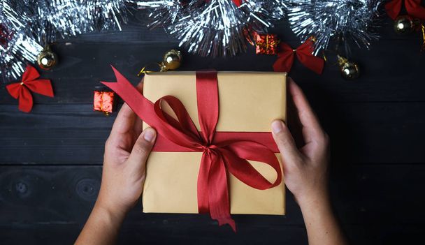 Noel hediyesi tutan el. Siyah ahşap tahta üzerinde gümüş Noel süs. Üstten görünüm - Fotoğraf, Görsel