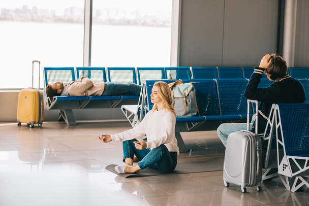 mladá žena přemýšlí v lotosové pozici při čekání letu v letištní terminál - Fotografie, Obrázek