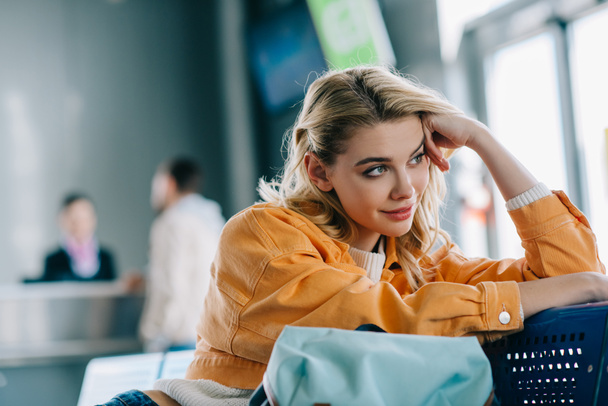 beautiful smiling girl sitting and looking away in airport terminal  - Photo, image