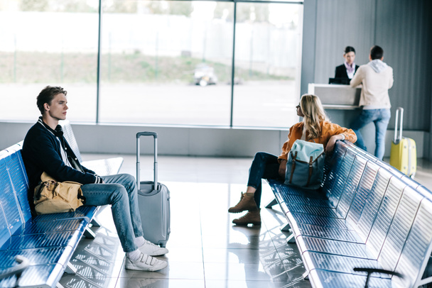 young people with luggage sitting and waiting for flight in airport terminal - 写真・画像