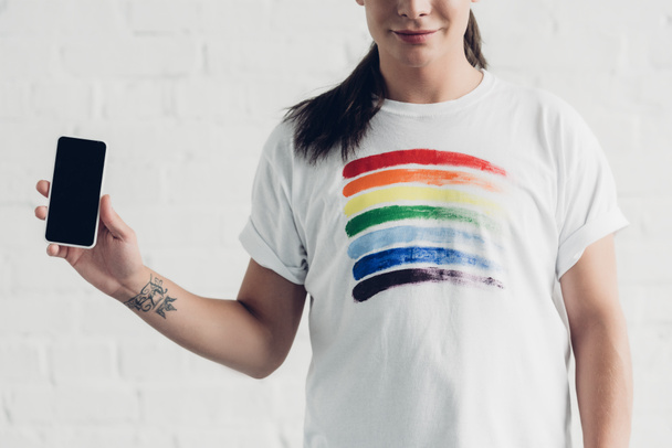 白いレンガの壁の前に白いTシャツを着た若いトランスジェンダーの女性の切り取られたショット - 写真・画像