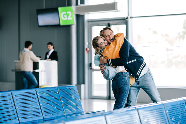 feliz joven hombre y mujer abrazándose en el aeropuerto
 - Foto, imagen