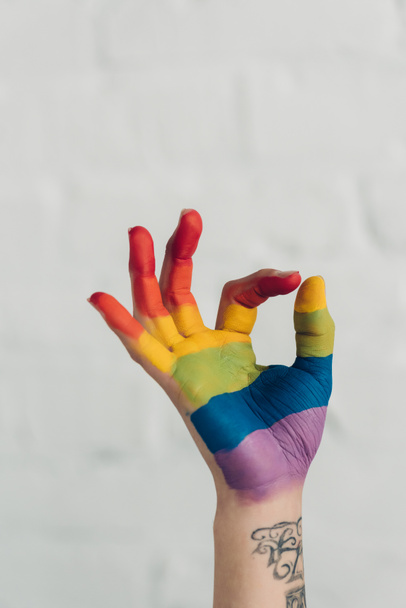 recortado tiro de mano pintado en colores de la bandera de orgullo mostrando gesto bien delante de la pared de ladrillo blanco
 - Foto, imagen