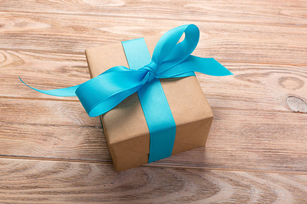 Одна подарункова коробка з синьою стрічкою дерев'яного столу. вид зверху
. - Фото, зображення