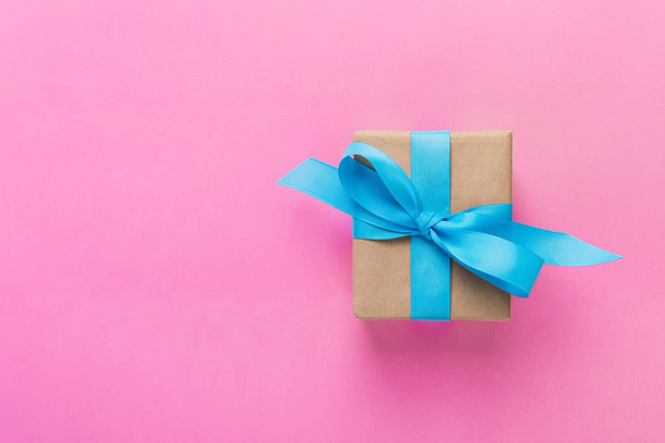 gift wrapped and decorated with blue bow on pink background with copy space. Flat lay, top view. - Фото, зображення