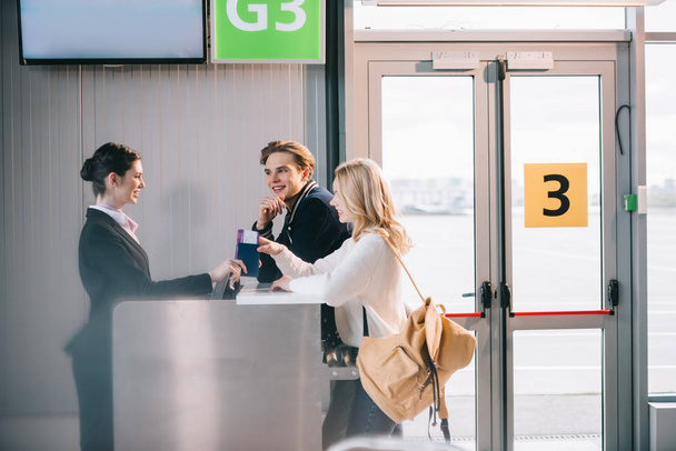 side view of happy young couple at check-in desk in airport  - Valokuva, kuva