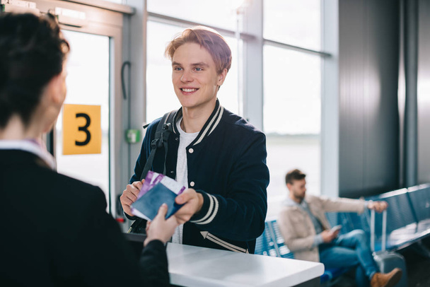 обрізаний знімок усміхненого чоловіка, який дає паспорт співробітникам аеропорту
 - Фото, зображення