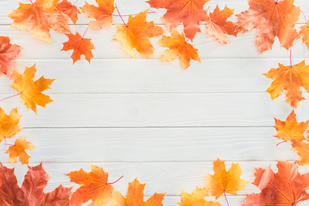 bovenaanzicht van frame van Oranje herfst esdoorn bladeren op houten oppervlak - Foto, afbeelding