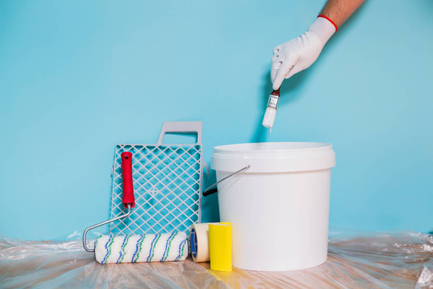 Image of equipment for painting wall and man holding paintbrush. - Photo, Image