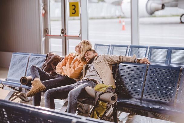 young couple sleeping while sitting together and waiting for flight in airport - Foto, afbeelding