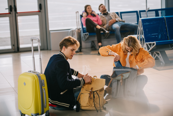 fiatalok látszó-ba hátizsák-míg a padlón ül és vár repülés, repülőtér - Fotó, kép