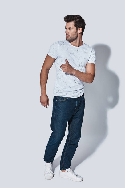 Full length of handsome young man in casual wear looking away while posing against grey background - Photo, image