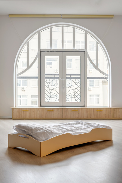 одне дерев'яне ліжко з білими постільними речами в світлій дитячій кімнаті
 - Фото, зображення