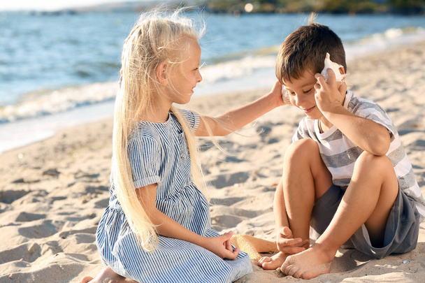 Pienet lapset leikkivät meren kuorilla rannalla
 - Valokuva, kuva