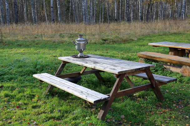 Un dispositivo per bollire l'acqua e fare il tè. Samovar tradizionale russo su un tavolo di legno sullo sfondo della natura autunnale
 - Foto, immagini
