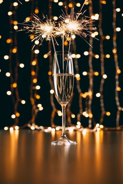 champagne with christmas sparkles on garland light background - Foto, Imagen