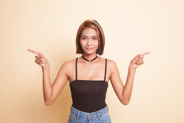 Young Asian woman point to left and right on beige background - Fotó, kép
