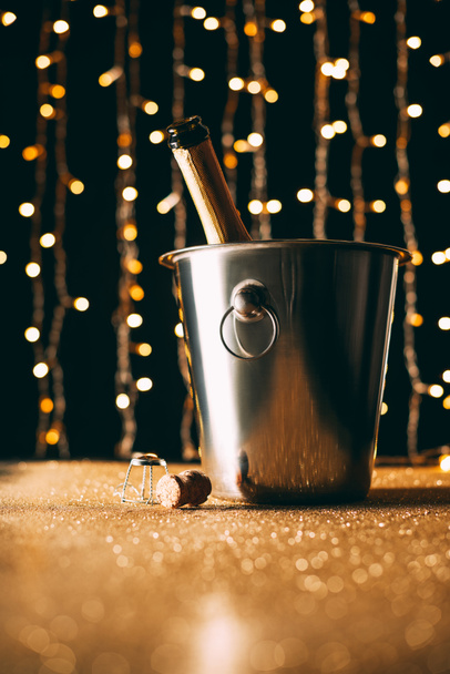 champagne bottle in bucket on garland light background, christmas concept - Photo, Image