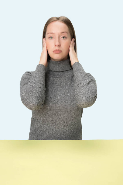 portrait of stressed woman sitting at table with closed and covering her ears with hands. - Photo, Image