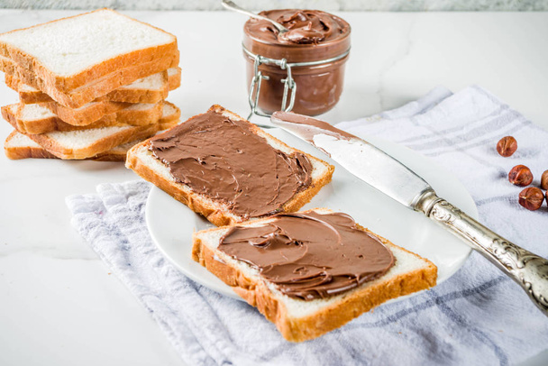 Sandwiches mit Schokolade und Haselnüssen mit weißem Toastbrot, weißem Marmor Hintergrund Kopierraum - Foto, Bild