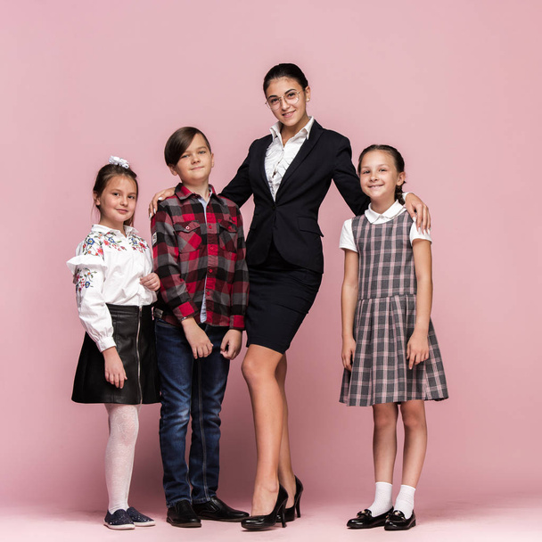 Cute stylish children on pink studio background. The beautiful teen girls and boy standing together - Foto, immagini