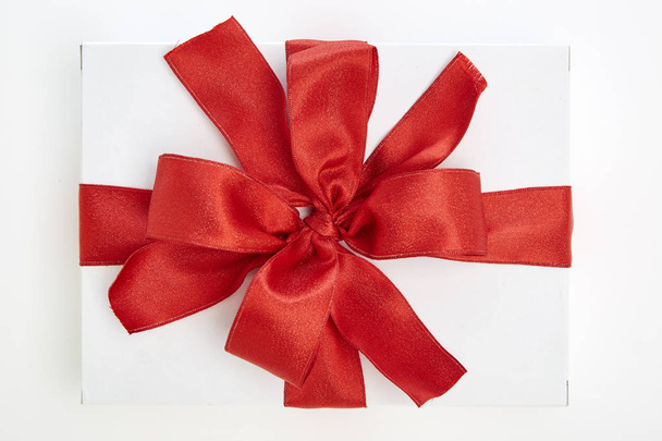 single white textured gift box with red ribbon bow on white background - Foto, immagini