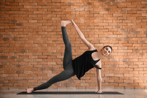 Young woman practicing yoga indoors - Фото, изображение